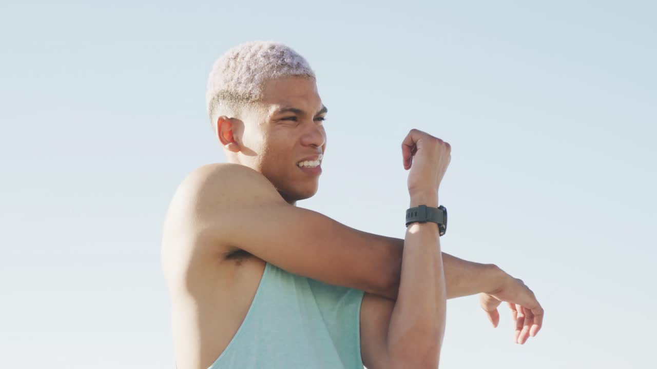 hombre biracial feliz estirándose en el paseo marítimo, en cámara lenta