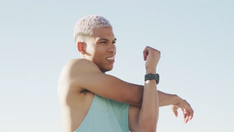 hombre biracial feliz estirándose en el paseo marítimo, en cámara lenta