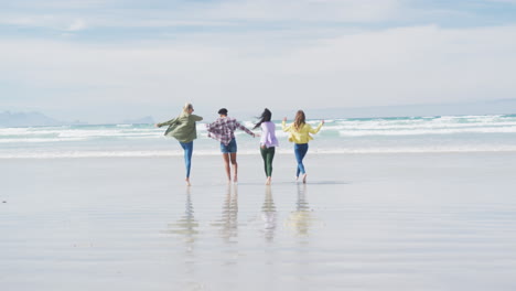 happy group of diverse female friends having fun, running at the beach