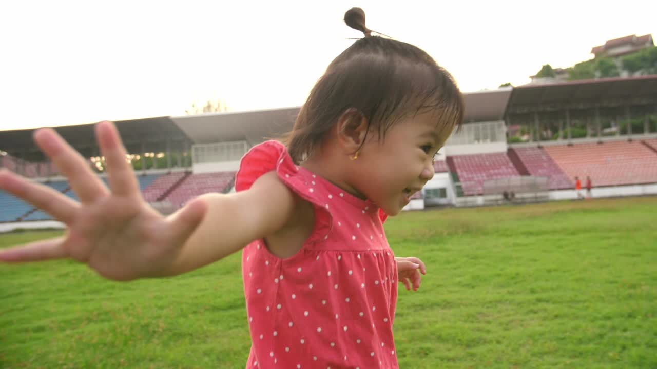 Happy Asian Little Girl Running On The Grass At Stadium