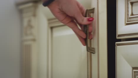 woman hand opening kitchen cupboard door and taking white plate on shelf inside