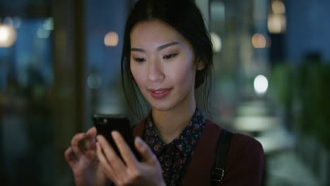 Retrato-De-Una-Joven-Mujer-De-Negocios-Asiática-Usando-Un-Teléfono-Inteligente-Navegando-Mensajes-En-Línea-Enviando-Mensajes-De-Texto-En-Un-Teléfono-Móvil-Por-La-Noche-Al-Aire-Libre-En-Cámara-Lenta-Estilo-De-Vida-De-Ocio