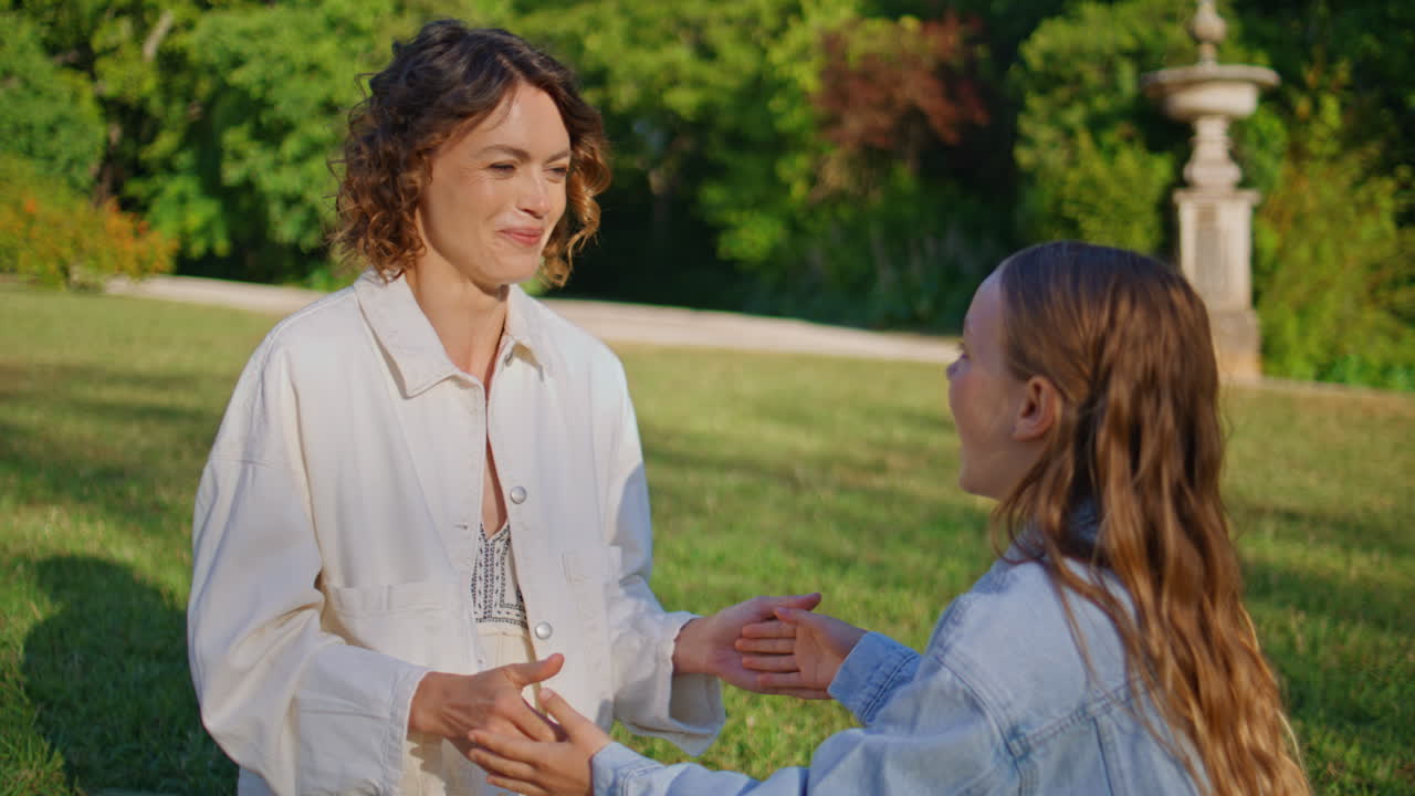 Closeup woman girl clapping hands at grass picnic. Mom daughter playing together
