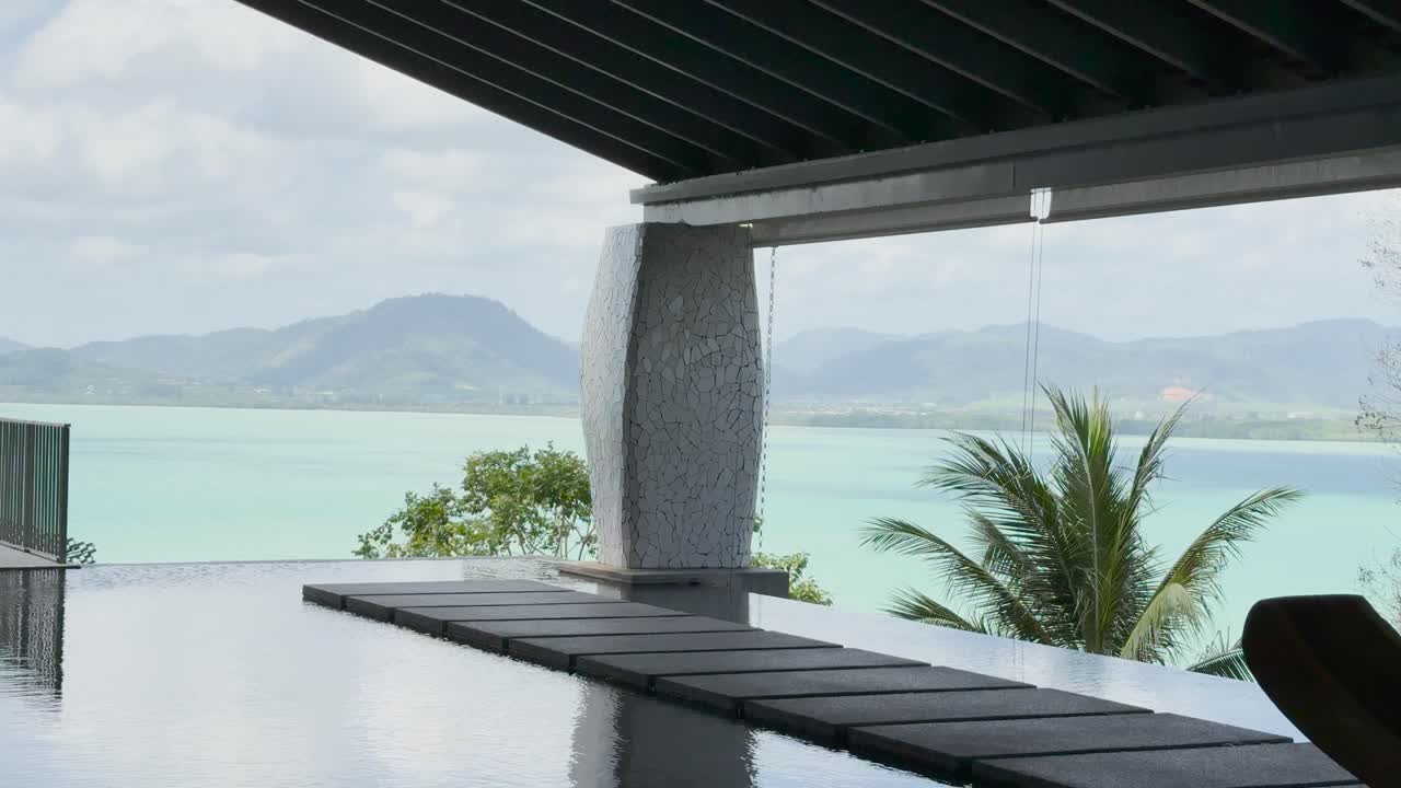 una vista tranquila de un complejo de lujo en phuket, que muestra una piscina infinita y una exuberante vegetación bajo la suave luz del día