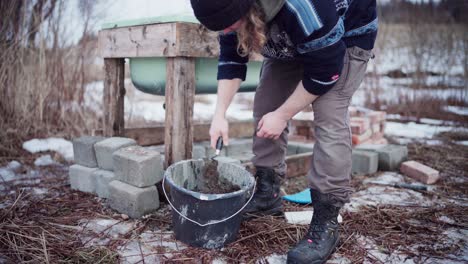 the man is blending the cement in the bucket required for constructing a diy hot tub - close up