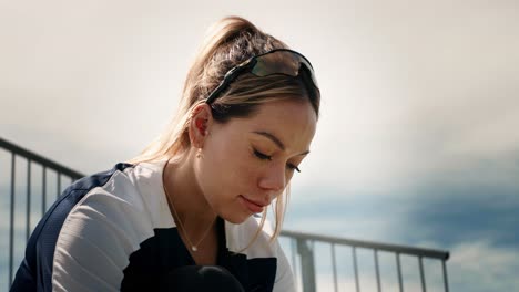 Female-athlete-is-looking-intensely-down-as-she-laces-her-shoes-while-sitting-on-a-row-of-bleachers