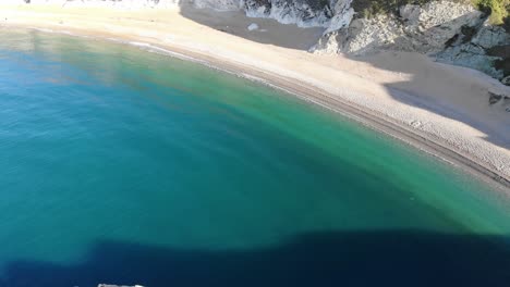 Aerial-Dolly-Back-Laibung-Der-Durdle-Door,-Umgeben-Von-Ruhigem-Türkisfarbenem-Wasser