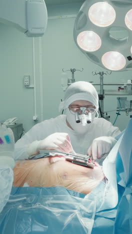 asistente da tubos delgados para la cirugía de bypass cardíaco. cardiólogo con colegas crear un nuevo camino para la sangre alrededor de la arteria bloqueada en la clínica en led lámparas quirúrgicas luz