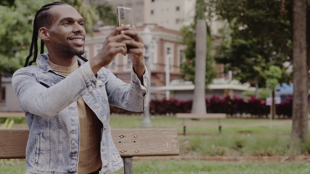 Young man taking photos or making a video call in a park