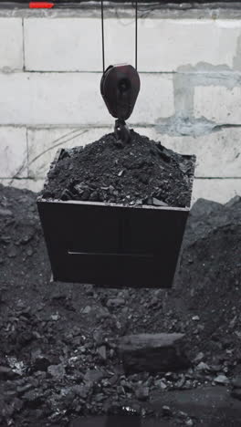 container with charcoal lifted by hoist out of pool at power production station. taking stone fuel for water heating furnaces. natural sources storage