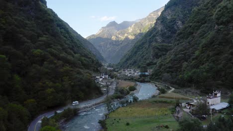 Drone-pulls-back-above-winding-blue-river-with-view-of-Yala-Snow-mountains-in-Western-China