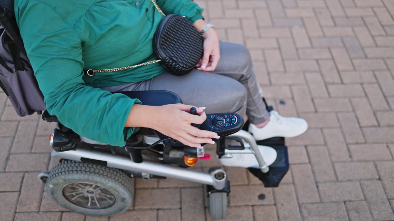 Person Operating Electric Wheelchair Joystick on Paved Surface