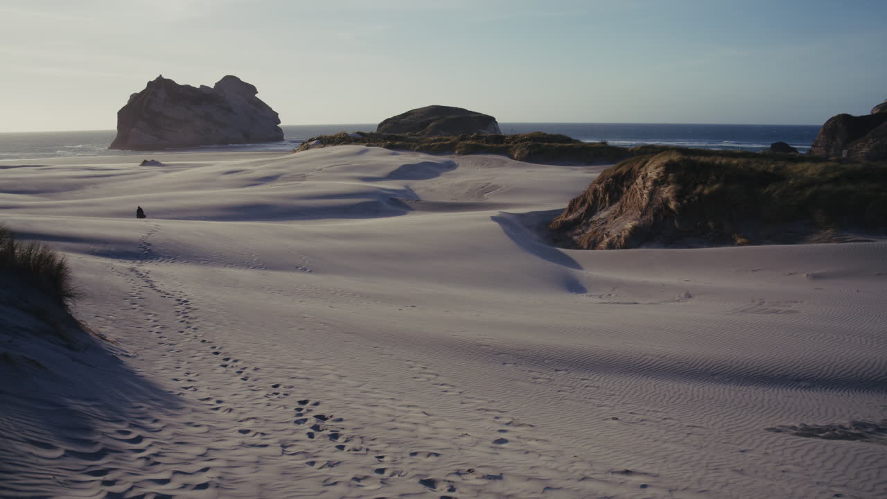 Sandy Beach Landscape with Footprints and Coastal Rocks