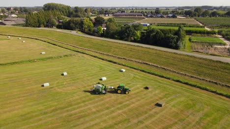 aerial following agriculture tractor packing hay balls in european village