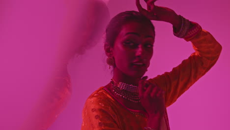 fotografía de estudio con reflejos de una bailarina de kathak que realiza un baile vestida con el vestido tradicional indio contra un fondo púrpura