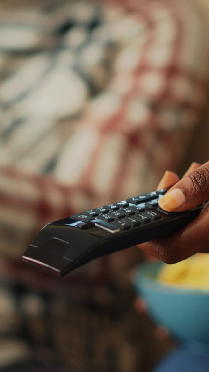 Video verticale: giovane ragazza che usa il telecomando della TV per guardare un film
