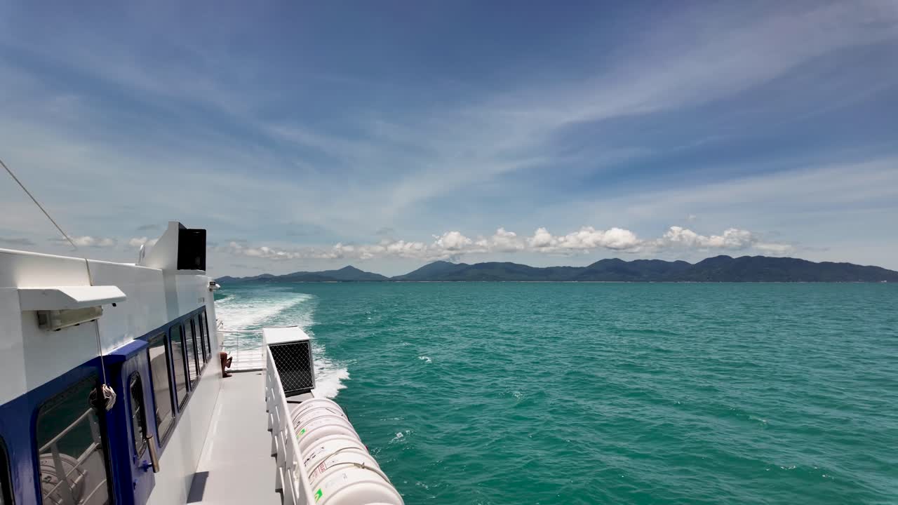 Sunny ferry ride between tropical islands in Thailand. Clear blue skies and turquoise waters create a serene journey