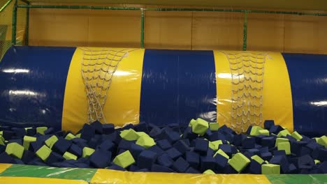 backside footage in slow-motion of a male jumping into apool with plush cubes.