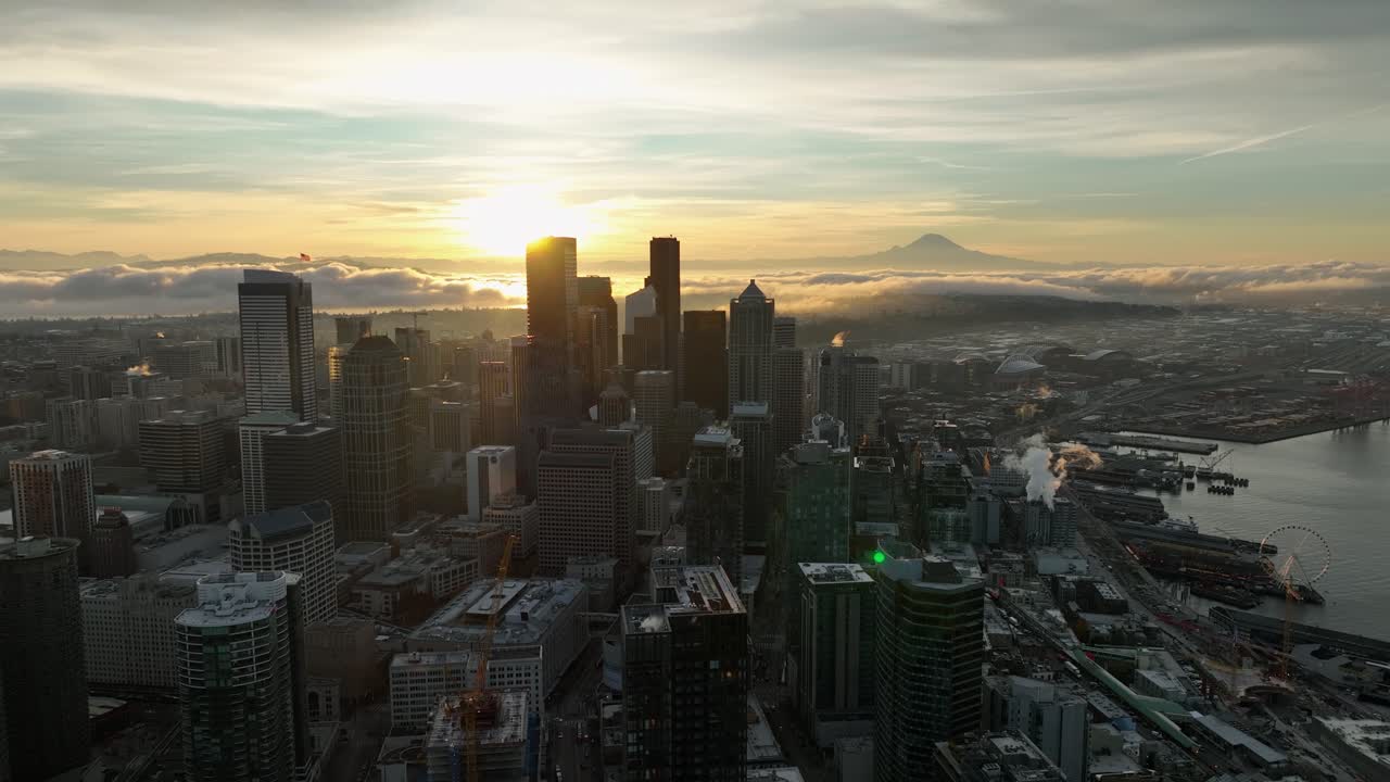 vista aérea del paisaje urbano de seattle iluminado por el amanecer sobre las nubes, subiendo hacia atrás