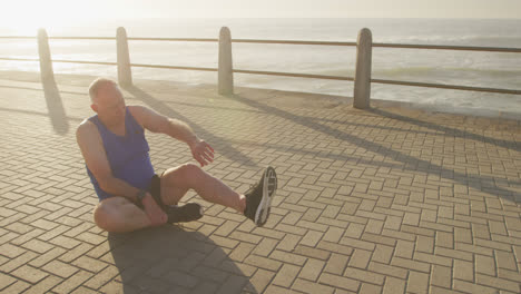 senior man stretching his legs on the promenade