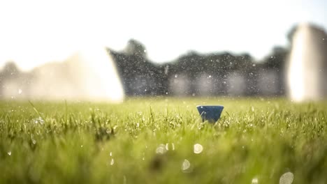 Golf-club-hits-a-golf-ball-in-a-super-slow-motion.-Drops-of-morning-dew-and-grass-particles-rise-into-the-air-after-the-impact.