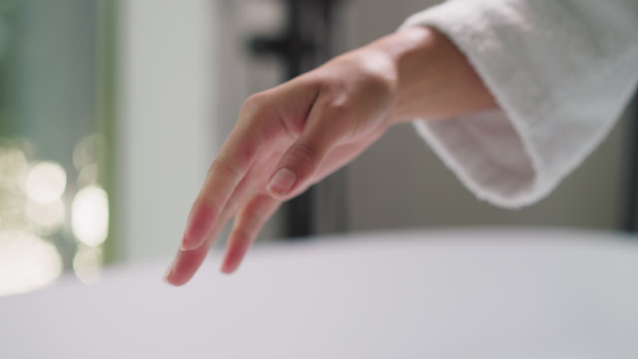 목욕탕에서 손가락을 흔들고 있는 여인 - 젊은 여인이 스파 살롱에서 목욕을 준비하는 소금 잔류물에서 손을 청소합니다.