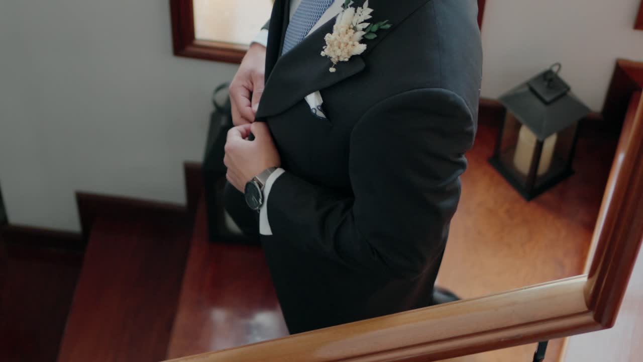 groom buttoning his elegant black suit with a silver watch before the ceremony