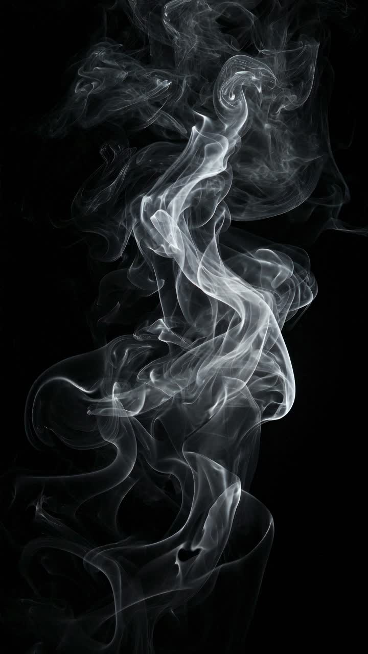 Volute eteree di fumo su uno sfondo nero, riprese da un angolo basso