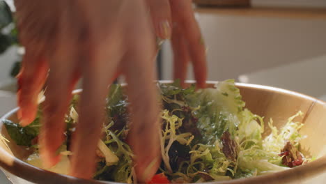manos de una mujer mezclando ensalada de verduras en un tazón