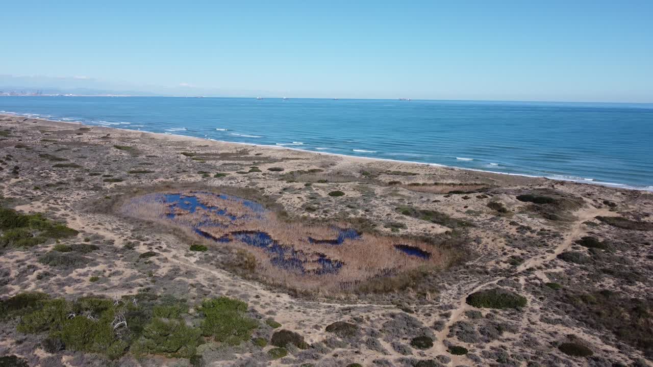 4K Aerial Drone Ascending Over Beach with Waves, Natural Lagoon, and Distant View of Valencia, Spain