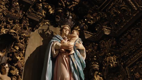 detailed religious sculpture of virgin mary holding baby jesus, surrounded by ornate golden woodwork