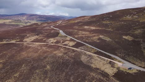 aerial flying over the cairngorms, cars traveling by road, scotland