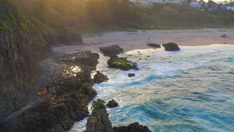 Tourists-On-Rocky-Coast-Near-Cave-At-Cathedral-Rocks-With-Sandy-Jones-Beach-In-Kiama-Downs,-New-South-Wales,-Australia