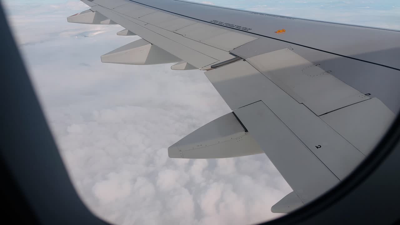 Aerial - airplane wing extending over a blanket of clouds during flight