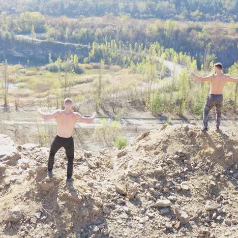 back view of athletic men running. active sportsmen without shirt show their trained body standing at the edge of a hill. aerial view.