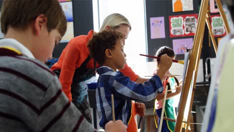 teacher assisting schoolboy in drawing class