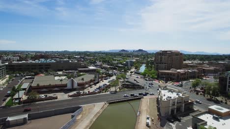 Aerial-slow-ascent-over-the-traffic-in-old-town-Scottsdale-at-the-intersection-of-Scottsdale-Road-and-Camelback,-Scottsdale,-Arizona