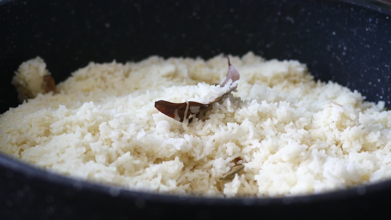 closeup de una olla de arroz blanco cocido con una hoja de laurel