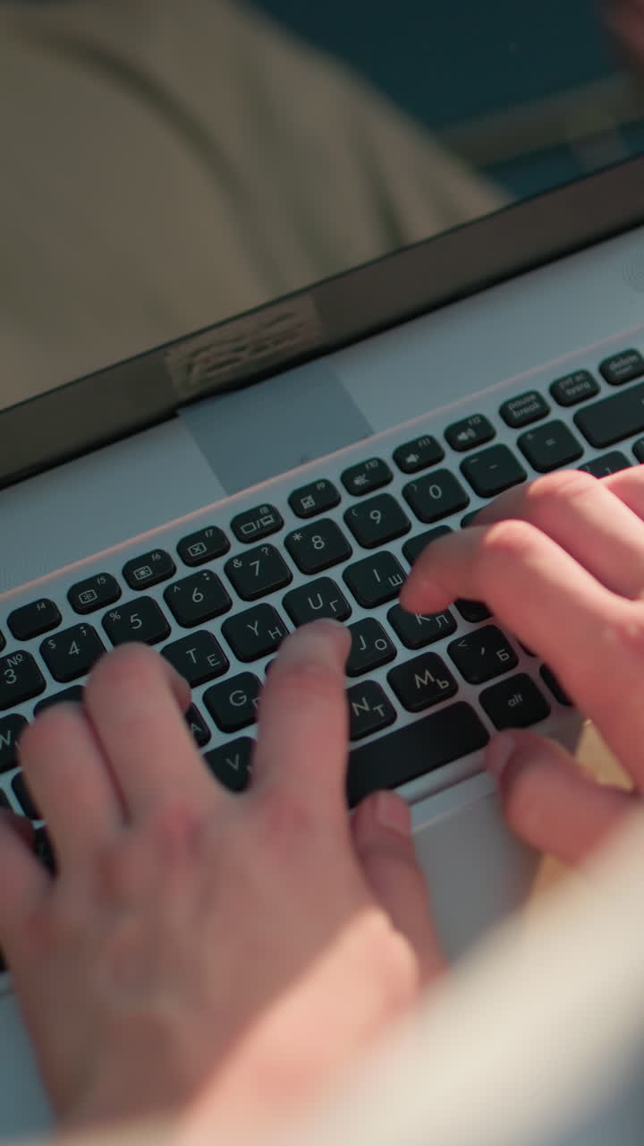 hombre escribiendo en el teclado de la computadora portátil al aire libre, el reflejo de las manos y la luz del sol visibles en la pantalla, creando una escena atractiva y serena, el fondo presenta iluminación sutil y un entorno borroso