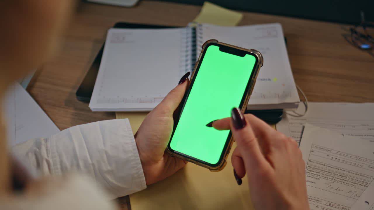 Primo piano di una donna d'affari che usa uno smartphone con chromakey mentre naviga sul web dal suo posto di lavoro