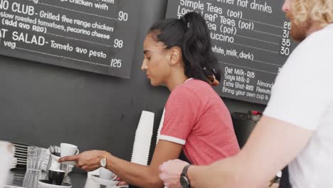 Happy-diverse-male-and-female-baristas-talking-and-having-coffee-in-cafe