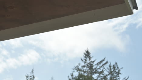 residential home, raindrops fall from eaves of roof