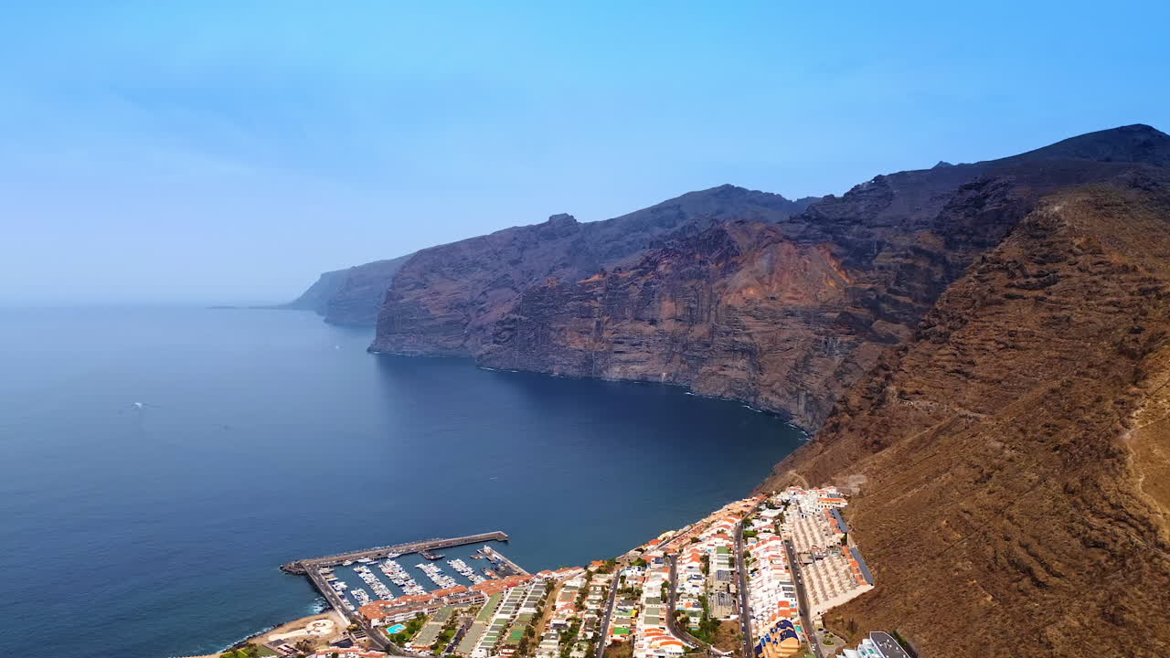 Spectacular bare rocks with no vegetation on. Residential area located on the slopes of the mountains at the coast of the Atlantic Ocean. Tenerife island, Spain. Aerial view