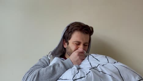 Young-Male-University-Student-Looking-Visibly-Unwell-Coughing-Whilst-Talking-to-Camera-On-Video-Call