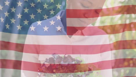 Animation-of-flag-of-usa-waving-over-smiling-african-american-woman-holding-flowers