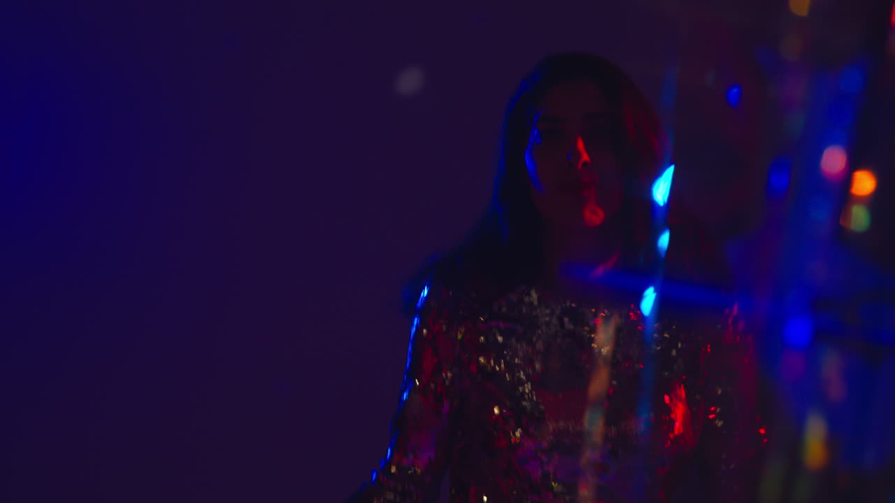 primer plano de una mujer divirtiéndose bailando en un club nocturno de discoteca o bar con oropel en primer plano