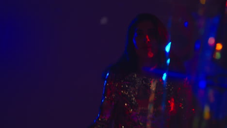 close up of woman having fun dancing in disco nightclub or bar shot with tinsel in foreground