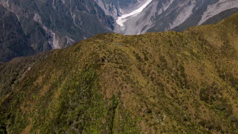 Drone-flyover-mountain-peak,-reveal-of-Fox-Glacier-surrounded-by-high-mountain-peaks,-beautiful-scenery-in-New-Zealand