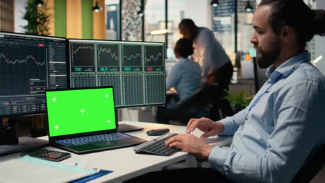 day trader in office analyzes stock market charts on isolated screen laptop