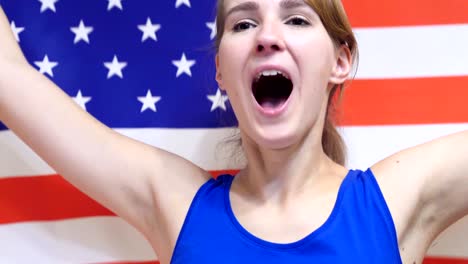 american young woman celebrating while holding the flag of america in slow motion